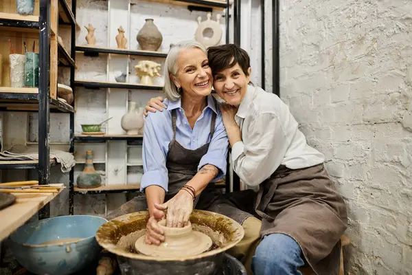 Two women in cozy clothes hug at pottery studio. — Stock Photo