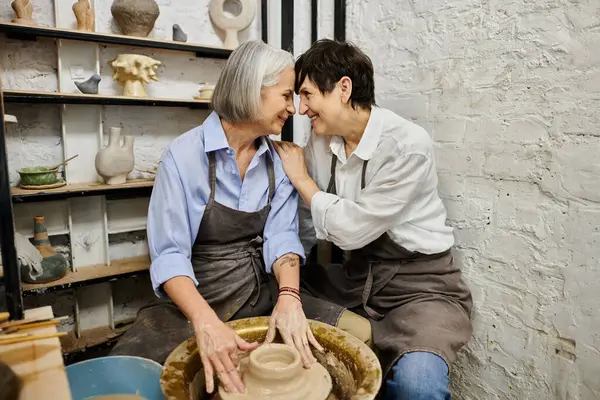 Un couple de lesbiennes matures travaille sur la poterie dans un studio d'art confortable. — Photo de stock