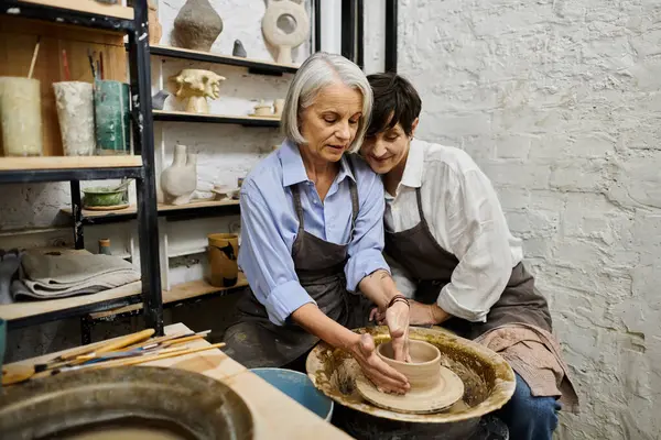 A mature lesbian couple works on a pottery project together in a cozy studio. — Stock Photo