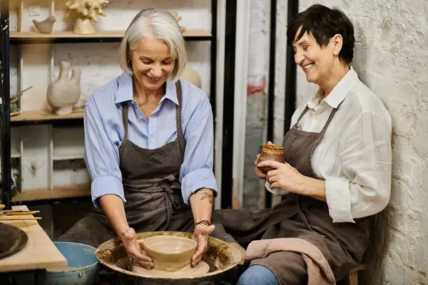 Two mature women work on pottery in a cozy studio. — Stock Photo