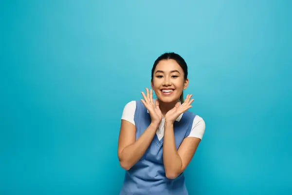 Молодая азиатка в элегантной повседневной одежде ярко улыбается на ярком синем фоне. — стоковое фото
