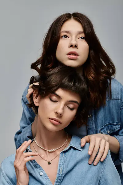 Two young women wearing denim shirts pose for a portrait against a gray background. — Stock Photo
