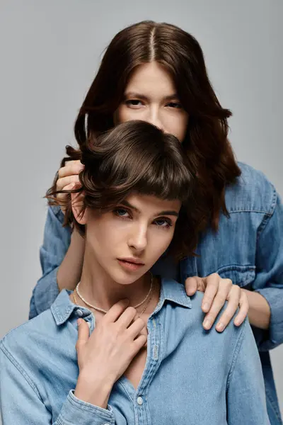 Two young women in denim shirts pose against a gray background. Lesbian couple — Stock Photo