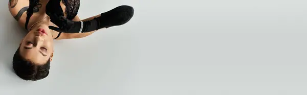 A woman in black lingerie poses on a white background. — Stock Photo