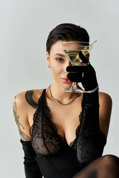 A woman in black lingerie poses with a martini, looking confident and seductive. — Stock Photo