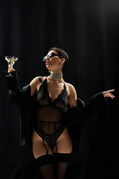 A woman in lingerie poses with a martini in hand, wearing sunglasses. — Stock Photo