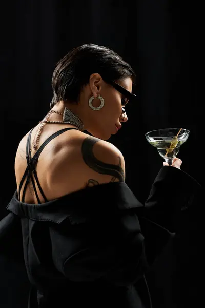 A woman in black lingerie poses suggestively, holding a martini. — Stock Photo