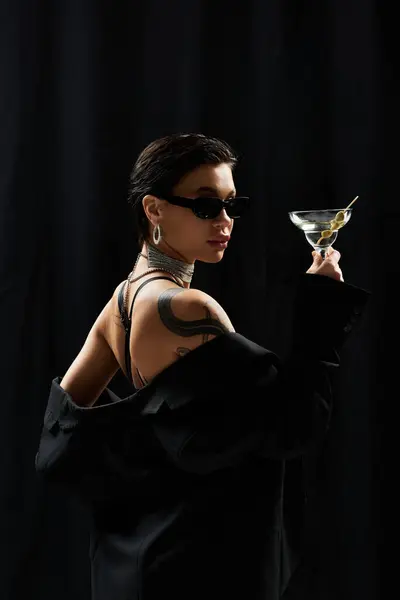 Una donna in lingerie nera e occhiali da sole tiene un martini. — Foto stock