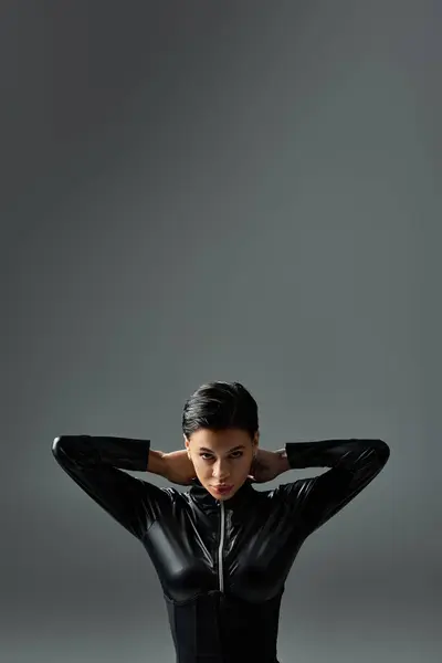 A young woman in black leather jumpsuit poses with a confident and seductive expression. — Stock Photo