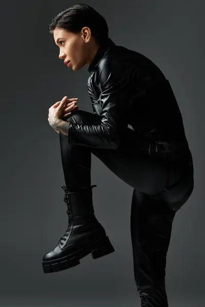 A woman in black leather jumpsuit poses seductively. — Stock Photo