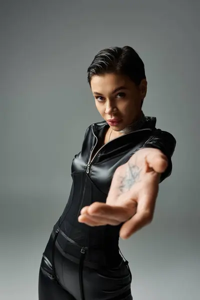 A woman in leather bodysuit poses seductively, hand outstretched. — Stock Photo