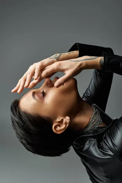 A woman in a black leather outfit poses seductively, her hands covering her face. — Stock Photo