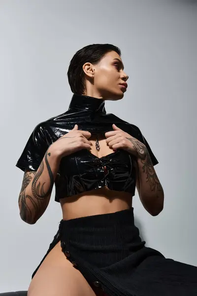 Una joven vestida de negro sexy posa contra una pared blanca. - foto de stock
