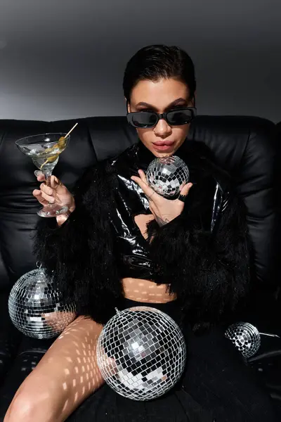 A woman in sexy attire sits with a martini and disco balls. — Stock Photo