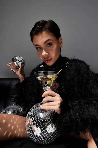 Uma mulher de traje sexy posa com um martini e uma bola de discoteca. — Fotografia de Stock