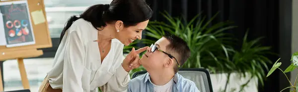 A mother working in her office, lovingly toughing nose of her son while he looks up at her with a smile. — Stock Photo