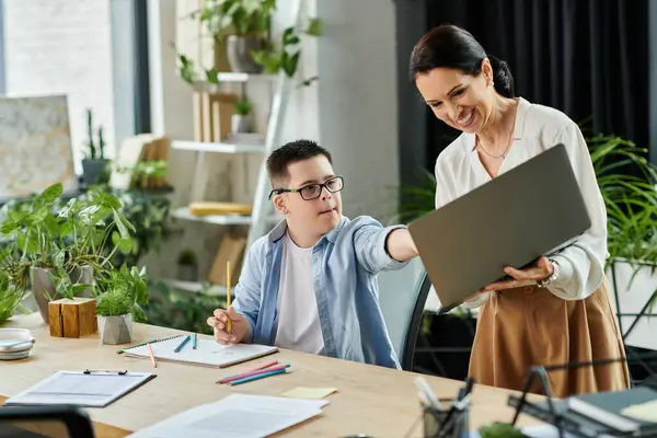 Una madre lavora nel suo ufficio al fianco di suo figlio con la sindrome di Down, mostrando diversità e inclusione sul posto di lavoro. — Foto stock