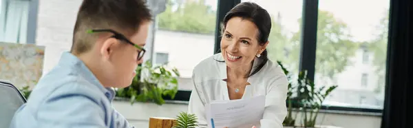 A mother and her son with Down syndrome are working together in an office setting. — Stock Photo