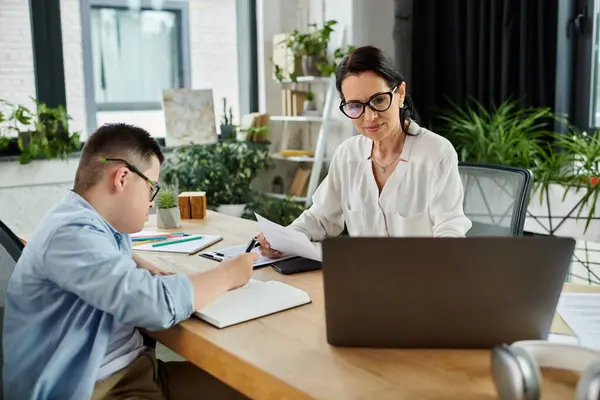 A mother and her son with Down syndrome work in an inclusive office, emphasizing diversity in the workplace. — Stock Photo