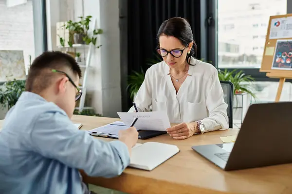 Una madre e un figlio, affetti dalla sindrome di Down, lavorano insieme in un ufficio moderno. — Foto stock