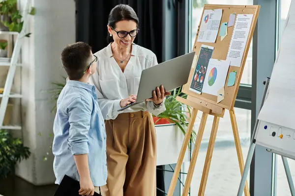 A mother and her son, who has Down syndrome, work together in an office setting, showcasing diversity and inclusion in the workplace. — Stock Photo