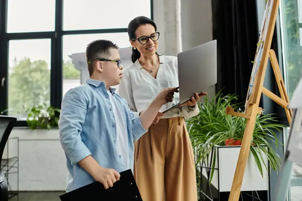 A mother and her son with Down syndrome work together in an office, showcasing diversity and inclusion in the workplace. — Stock Photo