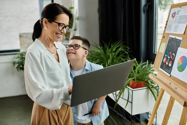 A mother and her son with Down syndrome work together on a laptop in an office setting. — Stock Photo