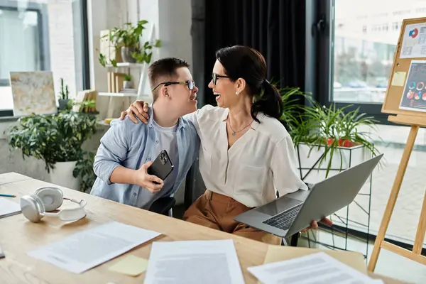 Madre e figlio con sindrome di Down condividono un momento gioioso in ufficio, mettendo in evidenza la diversità e l'inclusione sul posto di lavoro. — Foto stock