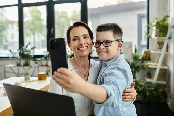 A mother working in her office takes a selfie with her son, who has Down syndrome, demonstrating a positive and inclusive work environment. — Stock Photo