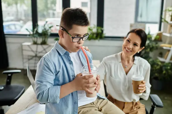 Una madre lavora nel suo ufficio al fianco di suo figlio con la sindrome di Down, dimostrando inclusività e amore. — Foto stock