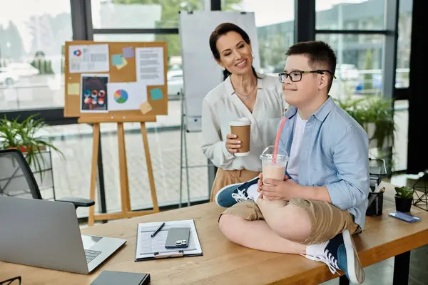 A mother and her son with Down syndrome enjoy a break together in the office. — Stock Photo