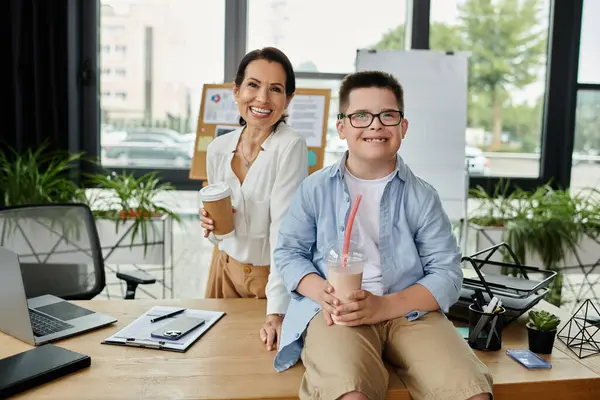 A mother and her son with Down syndrome are working together in an office. They both are smiling and holding drinks. — Stock Photo