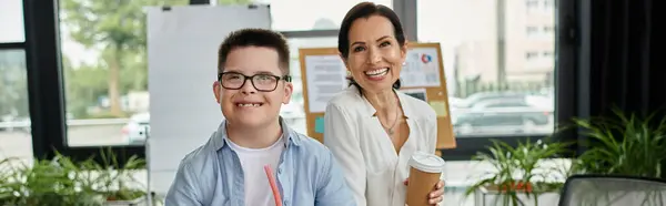 Eine Mutter und ihr Sohn mit Down-Syndrom arbeiten glücklich zusammen im Büro. — Stockfoto