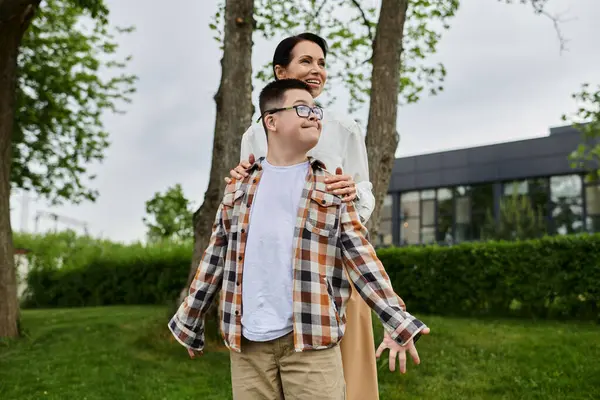 Una madre cammina con suo figlio con la sindrome di Down in un parco vicino a un edificio per uffici. Si stanno godendo la vita all'aria aperta insieme. — Foto stock