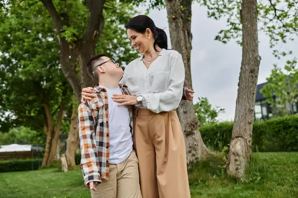 A mother and her son with Down syndrome walk together in a park, showcasing the beauty of diversity and inclusion. — Stock Photo