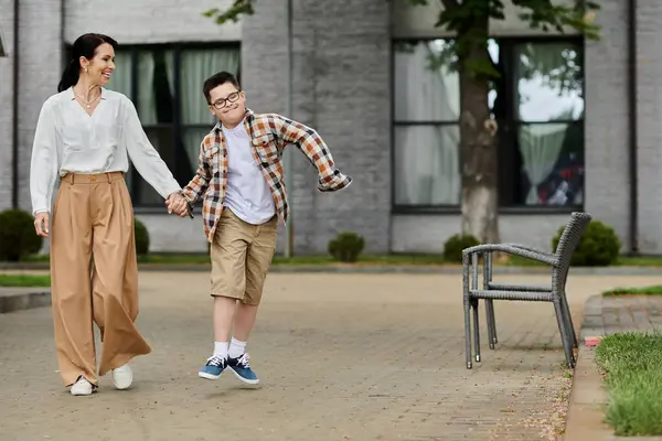 A mother walks hand-in-hand with her son, who has Down syndrome, outside near an office building. — Stock Photo