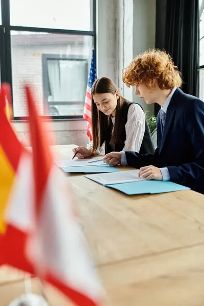 Two teenagers work together on a document during a Model United Nations conference. — Stock Photo
