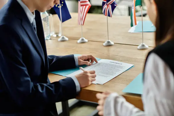 Two teenagers participate in a UN Model conference, signing a contract. — Stock Photo