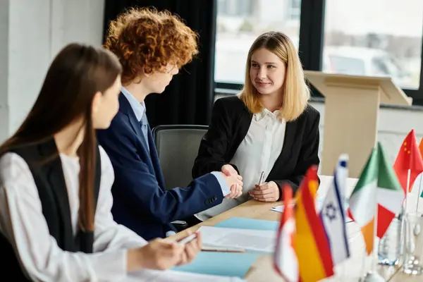 Gli adolescenti partecipano a una conferenza modello delle Nazioni Unite, stringendo la mano e discutendo questioni globali. — Foto stock