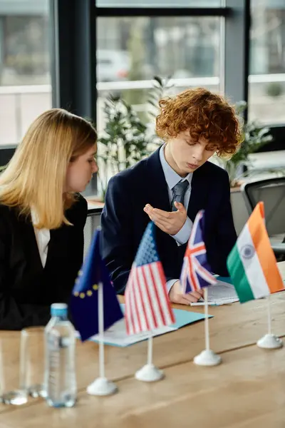 Два підлітки беруть участь у моделі ООН, представляючи різні країни з прапорами. — стокове фото