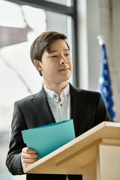 Teenage boy in a suit stands at a podium, ready to address a UN Model. — Stock Photo