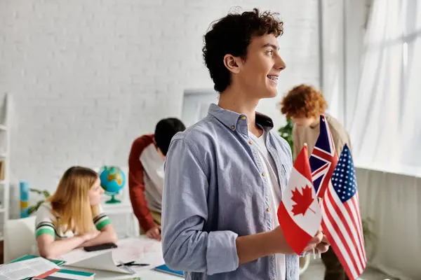 Teen boy holds flags of Canada, UK, US in model UN. — Stock Photo