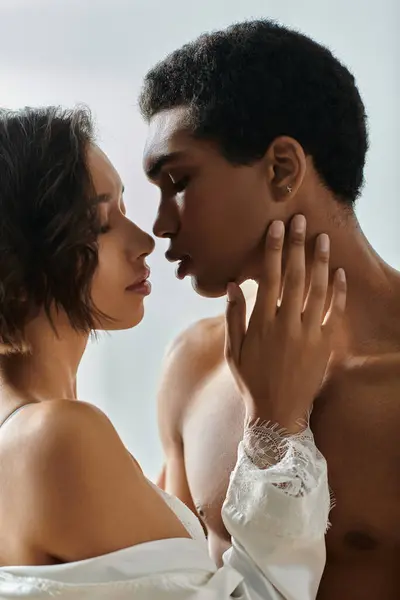 A young Asian woman and an African American man share a passionate kiss, their bodies pressed close in a tender embrace. — Stock Photo
