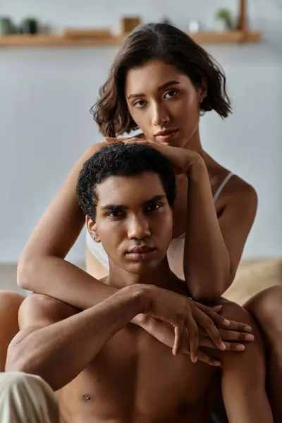 Una giovane coppia multiculturale condivide un abbraccio appassionato su un letto, il loro amore e la connessione palpabile. — Foto stock