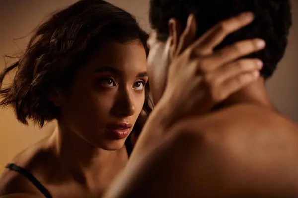 A young Asian woman in black lingerie seductively touches the back of an African American mans neck. — Stock Photo