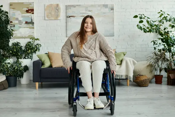 A young woman in a wheelchair smiles at the camera in her living room. — Stock Photo
