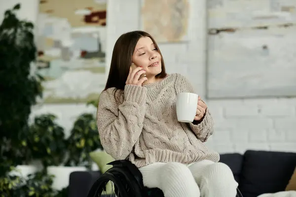 Eine junge Frau im Rollstuhl genießt ihren morgendlichen Kaffee und einen Anruf zu Hause. — Stockfoto