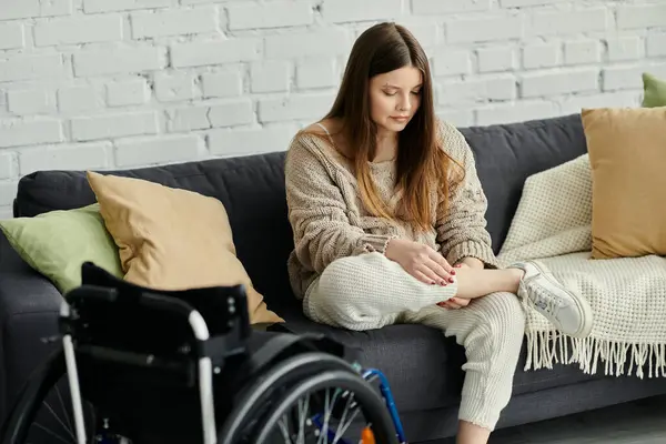 Eine junge Frau im Rollstuhl entspannt sich auf einer Couch in ihrem Haus. — Stockfoto