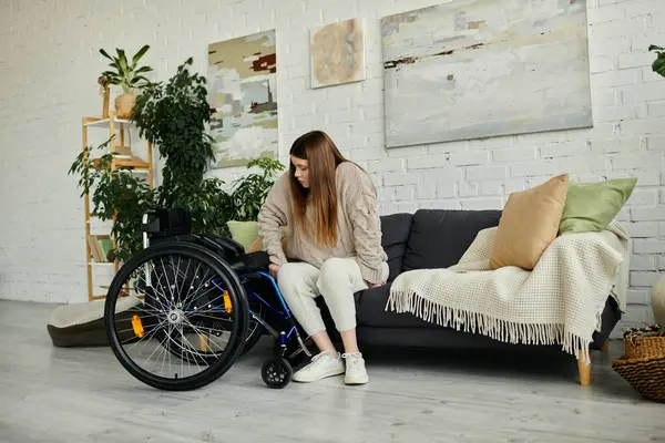 Eine junge Frau im Rollstuhl macht zu Hause eine Pause und ruht sich auf einem bequemen Sofa aus. — Stockfoto