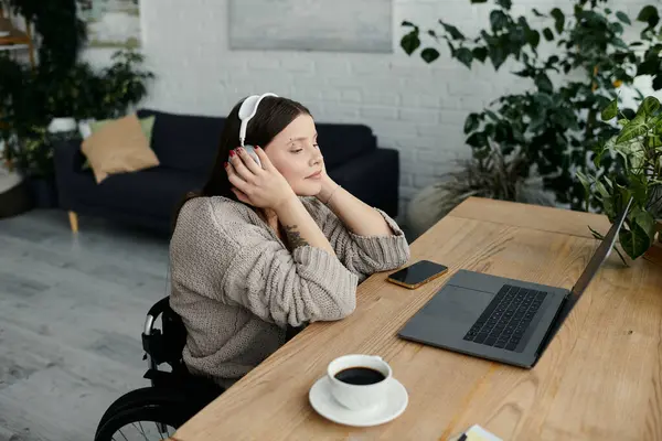 A young woman in a wheelchair enjoys a moment of peace at home, listening to music and enjoying a cup of coffee. — Stock Photo